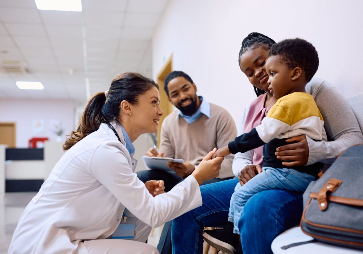 Doctor examining a young boy while parents watch attentively.